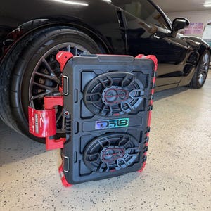 May include: A black and red speaker system with two speakers, the brand name DS18 is visible. The speaker system is in front of a black sports car. The speakers have a black and red design.