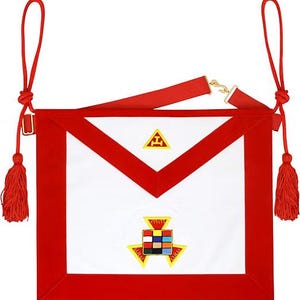 May include: A white ceremonial apron with a wide red border, featuring a triangular flap and two red tassels on cords. The apron displays a yellow embroidered triangle symbol on the flap and a multi-colored grid emblem on the main body.