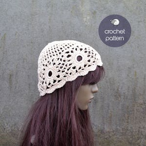 Può includere: Un cappello all'uncinetto con un delicato disegno floreale di colore crema. Il cappello è indossato da un manichino con lunghi capelli rosso scuro.