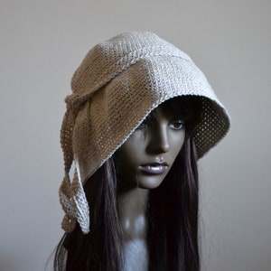 May include: A beige crocheted hat with a wide brim and a long tie. The hat is worn on a mannequin with long brown hair.