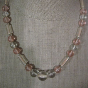 以下が含まれることがあります： ピンクと透明なガラスビーズのネックレスで、丸いビーズと長方形のビーズが交互になっています。