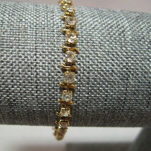 May include: A gold bracelet with clear rhinestones set in a zig-zag pattern.