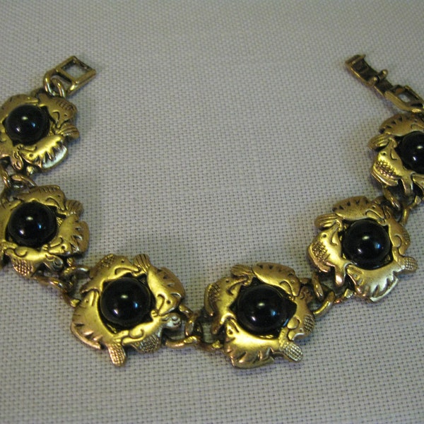 Pulseira cabochão preta embutida em tom dourado com moldura de peixe e fecho lagosta