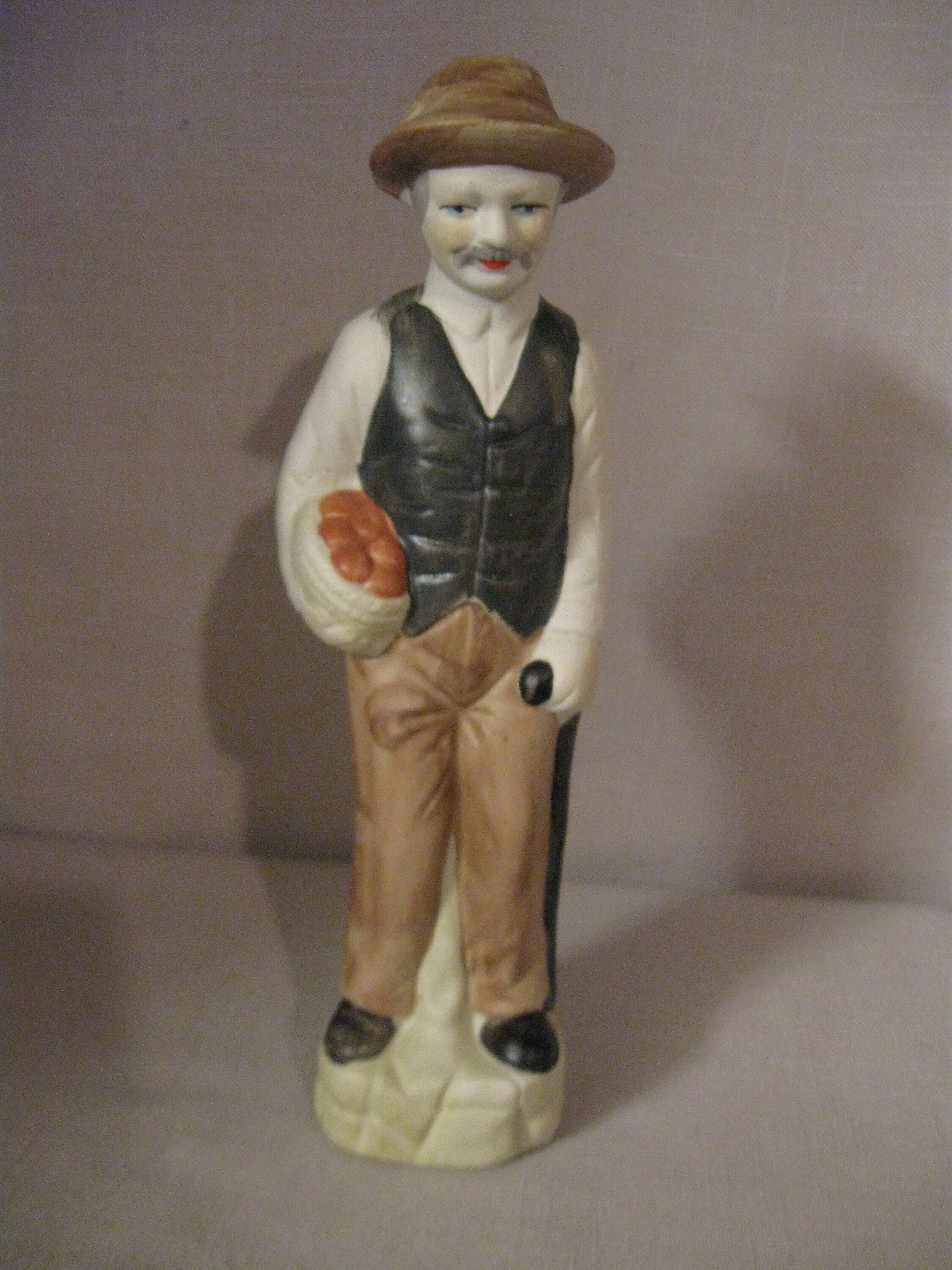Figurine Bisque Porcelain Man with Black Cane in Hand and Basket of Fruit or Vegetables Brown Hat Pants Black Vest White Shirt Not Mark 1980