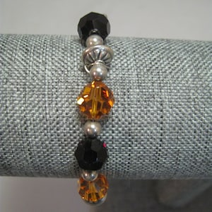 May include: A black and orange crystal bracelet with silver beads and spacers.