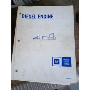 Puede incluir: Un manual blanco con tres perforaciones titulado DIESEL ENGINE en texto azul. Presenta un dibujo lineal azul de un edificio, el logotipo de GM y el texto Product Service Training. La esquina inferior derecha muestra el código 16015.00-1.