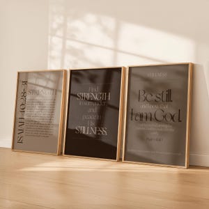 May include: Three framed art prints with inspirational quotes. The prints have a neutral color palette with gold frames. The first print has the text "ISAIAH 40:28-31" and "STRENGTH". The second print reads "Find STRENGTH in surrender, and peace in His STILLNESS". The third print says "Be still and know that I am God."
