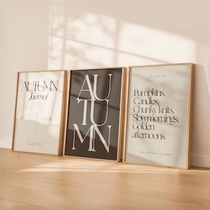 Könnte beinhalten: Drei rechteckige Wandbilder in hellen Holzrahmen. Das linke Bild ist cremefarben mit dem Text "AUTUMN Journal ISSUE NO 01 THE SEASON OF SLOW LIVING". Das mittlere Bild ist dunkelbraun mit dem Wort "AUTUMN" in großen weißen Buchstaben. Das rechte Bild ist cremefarben mit dem Text "A LIST OF Pumpkins, Candles, Chunky knits, Slow mornings, Golden afternoons. THE SIMPLE THINGS".