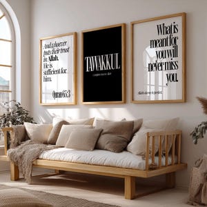 May include: Three framed wall art pieces with inspirational quotes in black and white. The middle frame is black with the word "TAWAKKUL". The other two frames have white backgrounds with quotes. A wooden daybed with pillows is in the foreground.