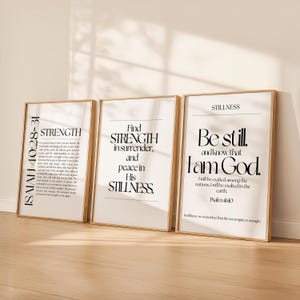 May include: Three framed art prints with inspirational quotes in black text on a white background. The frames are a light wood color. The prints feature the words "Strength", "Find Strength", and "Be Still".