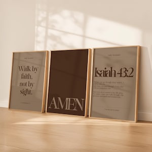 May include: Three framed prints with gold-coloured frames. The left print reads "Walk by faith, not by sight." The centre print says "AMEN." The right print features the text "Isaiah 43:2" and a Bible verse. The prints have a neutral colour palette.