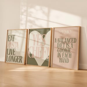 May include: Three framed art prints with gold frames. The prints feature text in a modern font. One says "EAT PASTA LIVE LONGER", another says "YES CHEF!" over a heart, and the third says "A BALANCED DIET IS A COOKIE IN EACH HAND".