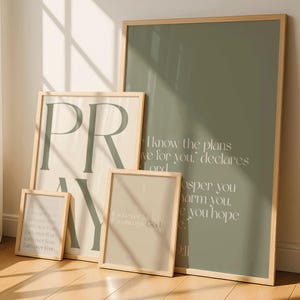 Puede incluir: Cuatro impresiones artísticas enmarcadas con citas inspiradoras. La impresión más grande es verde oliva con texto blanco. Otra impresión dice "PRAY". Las otras tienen citas sobre la fe. Todas tienen marcos de madera clara.