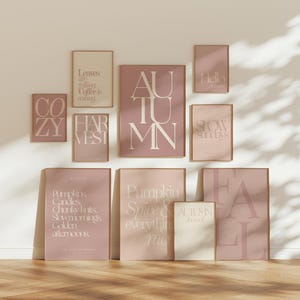 Könnte beinhalten: Ein Galerie-Wandset aus zehn gerahmten Postern in den Farben Mauve, Altrosa und Creme. Die Drucke zeigen Typografie mit Phrasen wie Leaves are falling, Coffee is calling, COZY, HARVEST, AUTUMN, Hello Autumn, SLOW SUNDAYS und FALL.