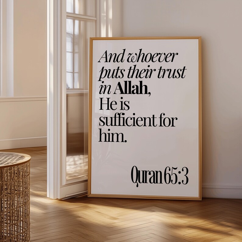 May include: A framed print with a light wood frame. The print has black text on a white background. The text reads "And whoever puts their trust in Allah, He is sufficient for him. Quran 65:3". The print is displayed in a room with a wooden floor.