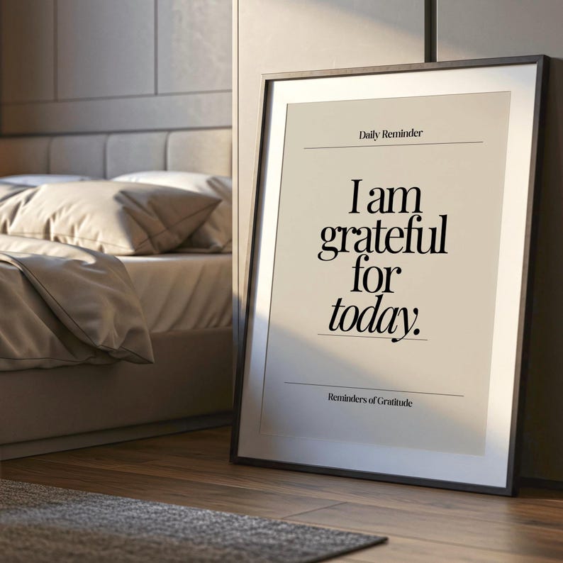 May include: A framed print with the text "I am grateful for today" in a bedroom setting. The print has a black frame and a neutral background. The words "Daily Reminder" and "Reminders of Gratitude" are also printed on the artwork.