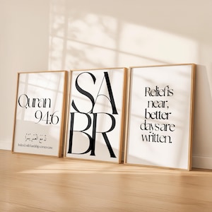May include: Three framed art prints with gold-coloured frames. The prints feature black text on a white background. One print says "Quran 94:6", another says "SABR", and the third says "Relief is near, better days are written."