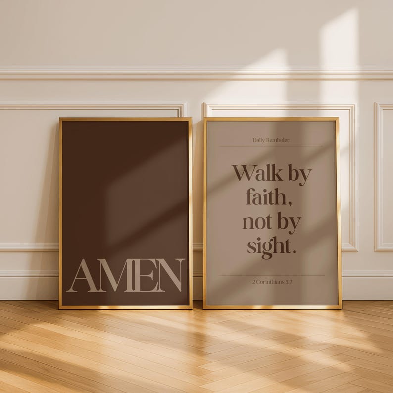 May include: Two framed art prints with gold trim. One print is a solid dark brown with the word "AMEN" in light beige. The other print is light beige with the text "Walk by faith, not by sight." and "2 Corinthians 5:7."