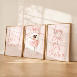May include: Three framed art prints in a ballet theme. The prints feature a pink colour scheme with the phrases "Little Dancer" and "Tiny Steps. Big Dreams." The central print showcases a ballerina in a pink tutu within an oval frame.