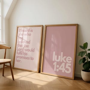 Könnte beinhalten: Zwei gerahmte Kunstdrucke mit Holzrahmen. Der linke Druck trägt den Text "Blessed is she who has believed that the Lord would fulfil his promises to her." Der rechte Druck zeigt "luke 1:45" in Weiß auf rosa Hintergrund.