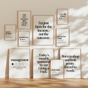 Könnte beinhalten: Eine Sammlung gerahmter Kunstdrucke mit humorvollen Zitaten in schwarzer Schrift auf weißem Hintergrund. Die Drucke sind in verschiedenen Größen und werden an einer hellen Wand ausgestellt. Die Rahmen sind hellbraun.