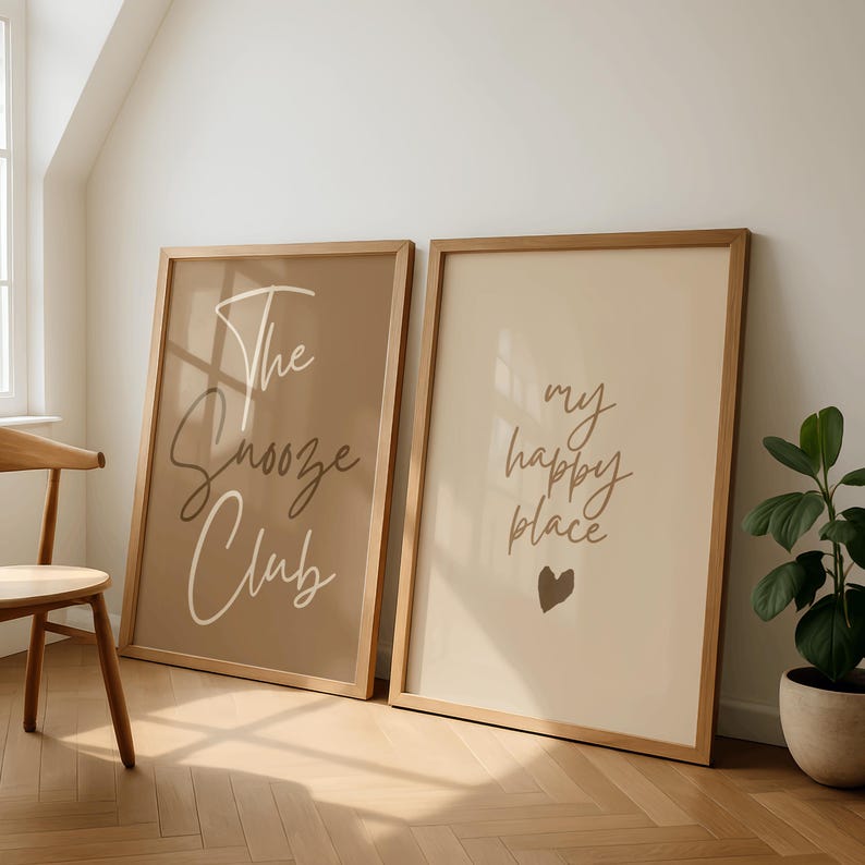 Pode incluir: Duas impress&otilde;es art&iacute;sticas emolduradas com molduras de madeira. Uma impress&atilde;o tem o texto "The Snooze Club" em estilo manuscrito sobre um fundo castanho. A outra impress&atilde;o tem o texto "my happy place" com um cora&ccedil;&atilde;o sobre um fundo creme.