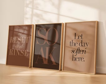 May include: Three framed art prints with gold-colored frames. The prints feature text in a serif font. The first print says "RESET and RINSE", the second says "SOAK", and the third says "Let the day soften here."