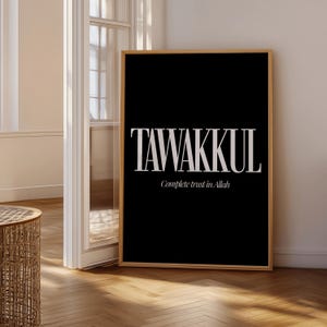 May include: A framed black art print with the word "TAWAKKUL" in large, white, serif font. Below, in a smaller font, it reads "Complete trust in Allah". The print is in a light wood frame.