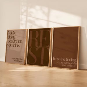 May include: Three framed art prints with motivational quotes. The first print says "You're doing better than you think" in a light brown color. The second print says "REST" in large letters. The third print says "Trust the timing."