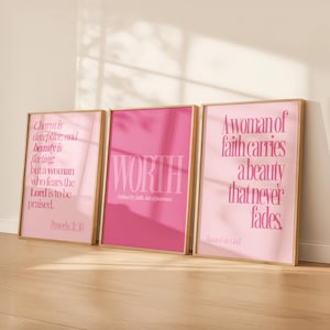 May include: Three framed art prints with inspirational quotes in pink hues. The prints feature text like "WORTH" and "A woman of faith carries a beauty that never fades." The frames have a gold finish, and the overall aesthetic is modern and motivational.