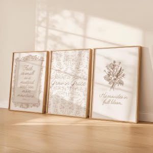May include: Three framed art prints with gold-coloured frames. The prints feature inspirational quotes and floral illustrations in neutral tones. The first print reads "Faith as small as a mustard seed can move mountains." The second print says "Grow in Grace." The third print says "He provides in full bloom."