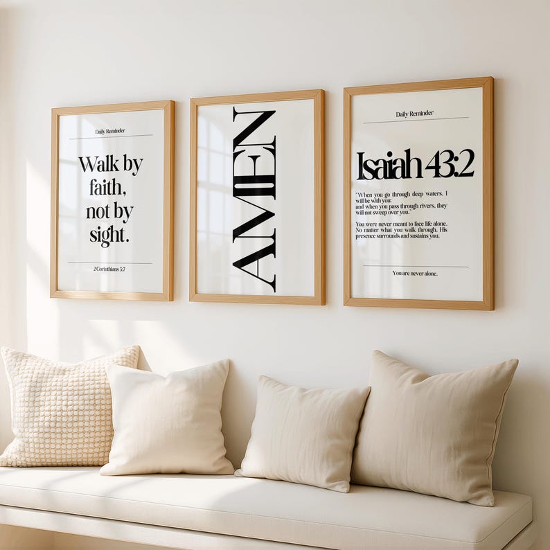 K&ouml;nnte beinhalten: Drei gerahmte Kunstdrucke mit inspirierenden Zitaten. Die Drucke haben einen hellen Holzrahmen und einen wei&szlig;en Hintergrund mit schwarzem Text. Der erste Druck lautet "Walk by faith, not by sight". Der zweite Druck lautet "AMEN". Der dritte Druck lautet "Jesaja 43:2".