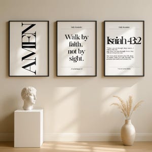 K&ouml;nnte beinhalten: Drei gerahmte Kunstdrucke mit schwarzen Rahmen. Der erste Druck sagt "AMEN" in gro&szlig;en, fetten Buchstaben. Der zweite Druck lautet "Walk by faith, not by sight." Der dritte Druck zeigt "Jesaja 43:2" mit einem Bibelvers.