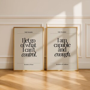 May include: Two framed art prints with gold frames. The left print reads "I let go of what I can't control." The right print reads "I am capable and enough." Both prints have a beige background and black text.