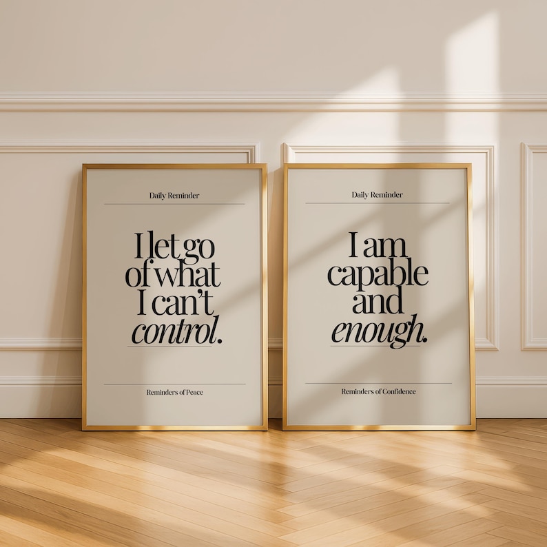 May include: Two framed art prints with gold frames. The left print reads "I let go of what I can't control." The right print reads "I am capable and enough." Both prints have a beige background and black text.