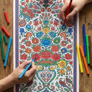 Puede incluir: Una página para colorear floral detallada con una variedad de flores rojas, azules, amarillas y verdes. Dos manos están coloreando la página con rotuladores rojos y azules. Una colección de rotuladores de colores está esparcida sobre una superficie de madera.