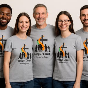 Puede incluir: Un grupo de personas con camisetas grises con un diseño gráfico. El diseño incluye una cruz negra, una forma de llama naranja y verde, y las palabras "body of Christ" con texto adicional. Las personas están sonriendo.