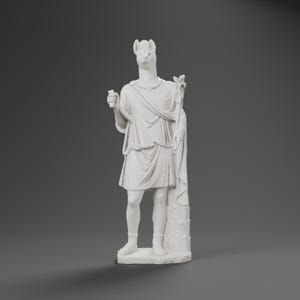 Puede incluir: Una estatua blanca de una figura con cabeza de animal, que viste una prenda drapeada estilo toga. La figura sostiene un objeto pequeño en la mano derecha y un bastón alto y ornamentado en la mano izquierda, sobre una base rectangular.