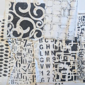 Könnte beinhalten: Eine Sammlung weißer Stoffmuster mit schwarzen Blockdruckmustern, darunter große Kreise, kleine Striche, geschwungene Schnörkel, Gitterquadrate, verschiedene Buchstaben des Alphabets und Ziffern, die in einer Collage angeordnet sind.
