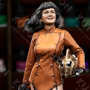 Peut inclure: Figurine détaillée d'une femme en uniforme marron, tenant un masque doré. Elle porte des bas noirs et des talons hauts. La figurine est une miniature, probablement pour collectionneurs ou amateurs. Le fond montre des flacons de peinture et le texte "Lychee Slicer PRE-SUPPORTED".