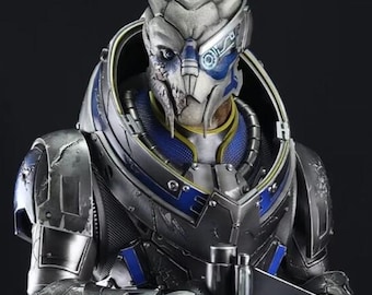 Op de afbeelding: Gedetailleerd beeld van een sciencefictionpersonage in metalen pantser, met een geweer. Het figuur zit op een platform met een gele helm in de buurt. Het beeld heeft blauwe en gouden accenten en een donkere achtergrond.