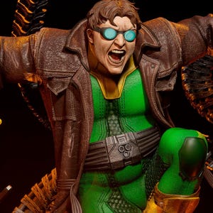 May include: A dynamic statue of a comic book character in a green and yellow suit, brown coat, and goggles. The figure is posed mid-action with mechanical tentacles extending from behind. The statue has a detailed design and is set against a dark background.