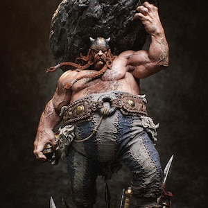 Op de afbeelding: Gedetailleerd beeldje van een gespierde Vikingfiguur, met rood gevlochten haar en een gehoornde helm, die een grote, donkere rots boven zijn hoofd optilt. De figuur draagt een blauw-grijze lappebroek en een versierde riem, met wapens aan zijn voeten.