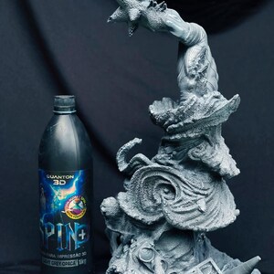 Pu&ograve; includere: Una scultura grigia stampata in 3D di una creatura fantastica con una mano a forma di stella, accanto a una bottiglia nera con un'etichetta blu e bianca. La bottiglia ha testo in portoghese. La scultura presenta dettagli e trame intricati.