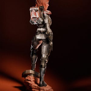 Puede incluir: Figura detallada de un personaje femenino con armadura futurista, vista desde atr&aacute;s. La figura tiene cabello rojo y una mochila con detalles rojos y blancos. La armadura es principalmente plateada y negra, sobre una base marr&oacute;n rojiza.