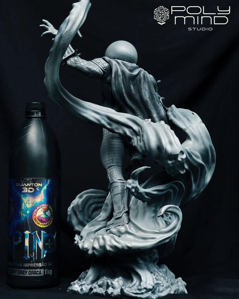 May include: A grey 3D-printed statue of a character in a dynamic pose, with flowing fabric and a spherical head. A dark grey bottle with text in Portuguese is in the foreground. The statue is on a black background.