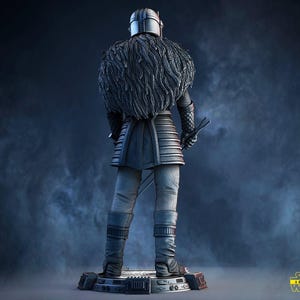 May include: A detailed statue of a character from Star Wars, viewed from the back. The figure is clad in dark armor with a fur-like collar and holds two swords. The base is a detailed platform. The Star Wars logo is visible in the bottom right corner.