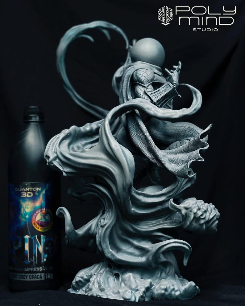 May include: A grey 3D-printed sculpture of a character with a spherical head and flowing cape. The figure is posed dynamically, with intricate details in the cape and costume. A bottle of "QUANTUM 3D" paint is next to the sculpture.