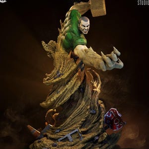 Pu&ograve; includere: Statua dettagliata stampata in 3D di un personaggio dei fumetti, con una figura muscolosa che emerge da una tempesta di sabbia vorticosa. Il personaggio indossa una maglietta verde e ha un'espressione determinata. La base include detriti e un segnale di stop rosso.