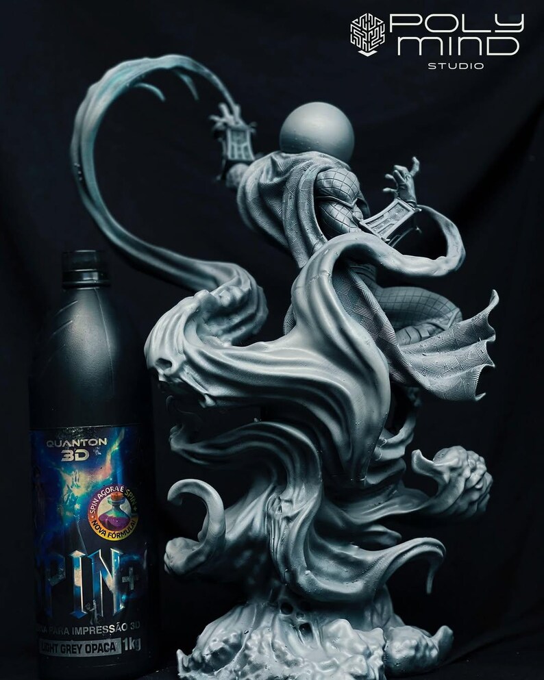 May include: A grey statue of a character with a spherical head, wearing a cape, and holding a book. The statue is on a swirling base. A bottle of "QUANTON 3D" resin is to the left. The Poly Mind Studio logo is in the upper right.